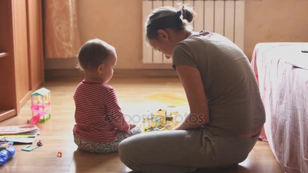 Мать и ребенок играют в комнате, сидя на полу . — стоковое видео