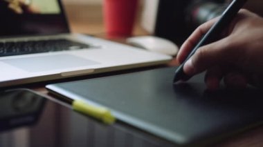 Bir grafik tablet ile bir dizüstü bilgisayar üzerinde çalışan tasarımcı.