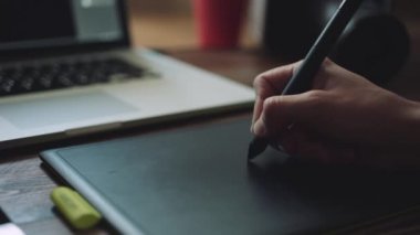 Bir grafik tablet ile bir dizüstü bilgisayar üzerinde çalışan tasarımcı.
