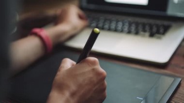 Grafik tabletli bir dizüstü bilgisayarda çalışan kadın tasarımcı.