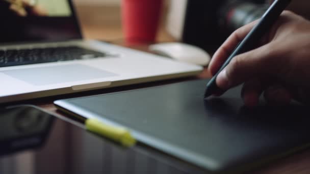 Ontwerper werkt aan een laptop met een grafisch tablet gebruikt. — Stockvideo