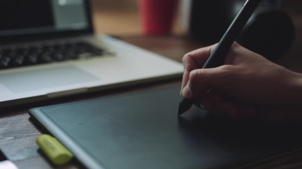 Designer trabalhando em um laptop com um tablet gráfico . — Vídeo de Stock