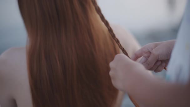 Жінка плете дівчину на пляжі — стокове відео