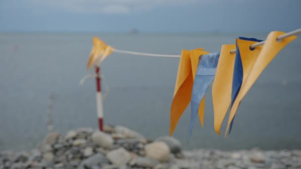 Banderas decorativas ondeando en el viento en la playa . — Vídeo de stock