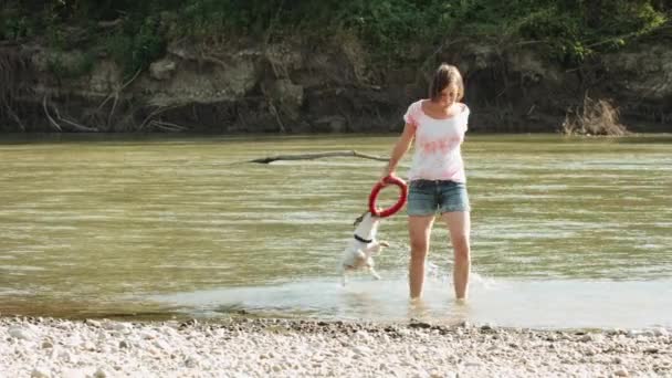 Mujer jugando con perro cerca del río — Vídeos de Stock