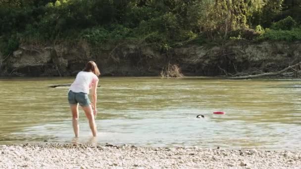 강 근처에 강아지와 함께 재생 하는 여자 — 비디오