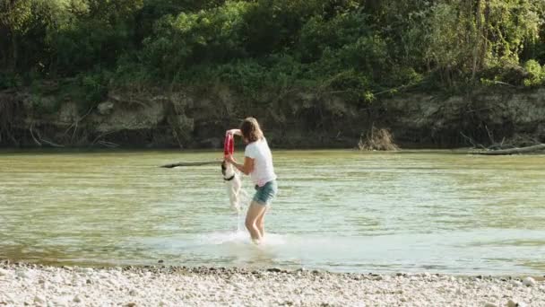 女人和河附近的狗玩 — 图库视频影像