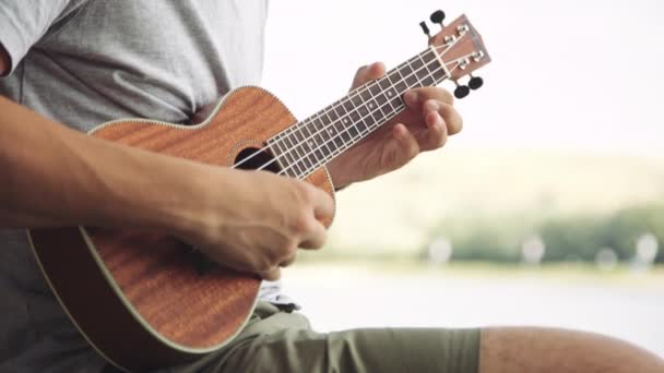 Человек, играющий на маленькой гитаре укулеле — стоковое видео