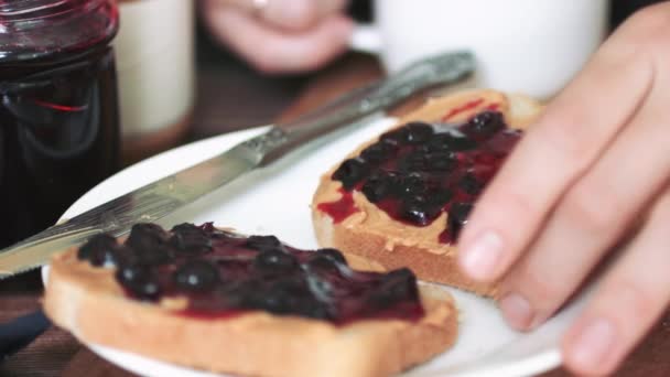 Mujer comiendo sándwich con mantequilla de maní y mermelada . — Vídeos de Stock