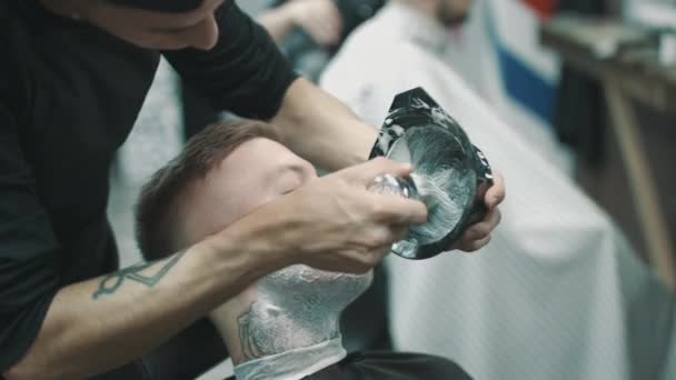 Barbeiro colocando creme de barbear em um cliente . — Vídeo de Stock
