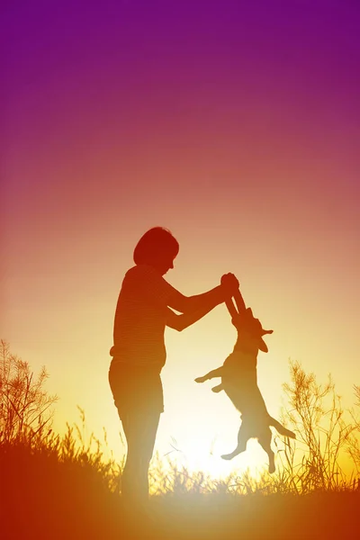 Silueta de mujer jugando con un perro . — Foto de Stock