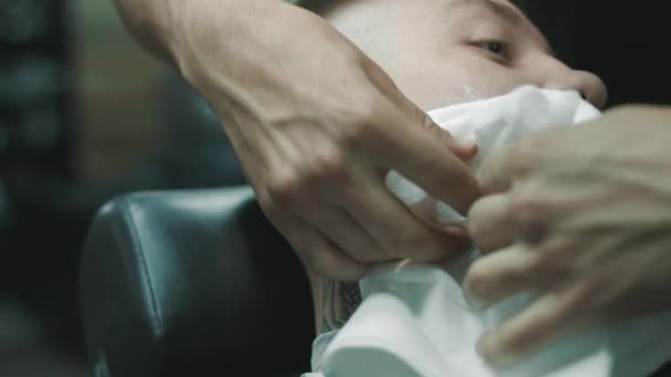 Barbeiro limpa com um guardanapo a cara do cliente . — Vídeo de Stock