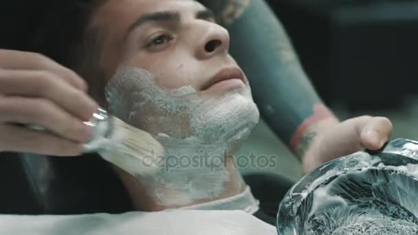 Barber putting some shaving cream on a client. — Stock Video