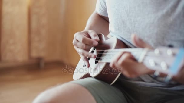 Человек, играющий на укулеле внутри — стоковое видео