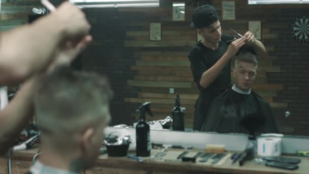 O barbeiro faz o corte para um cliente na barbearia . — Vídeo de Stock