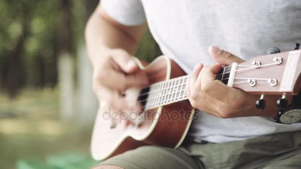 Людина грає на маленькій укулелевій гітарі — стокове відео