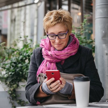 Telefonu kafede ile gülümseyen kadın