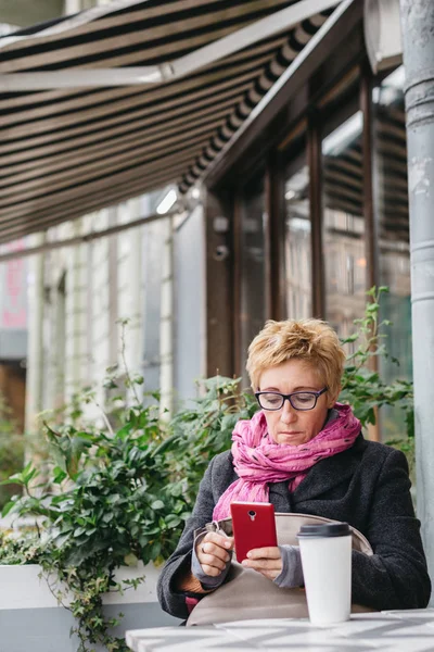 Telefonu kafede ile gülümseyen kadın