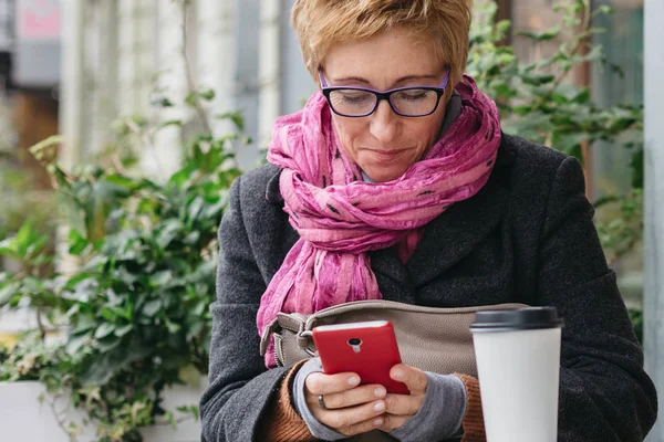 Telefonu kafede ile gülümseyen kadın
