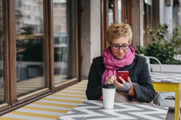 Mujer adulta con café y smartphone — Foto de Stock