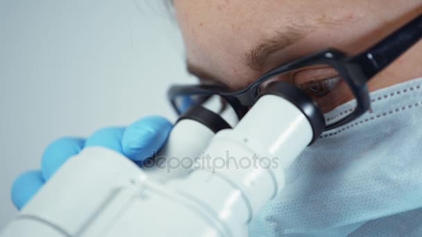 Científico en uniforme mirando microscopio — Vídeo de stock