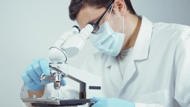 Científico en uniforme mirando microscopio — Vídeo de stock