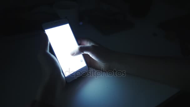 Vrouw maakt gebruik van een slimme telefoon in een donkere kamer — Stockvideo