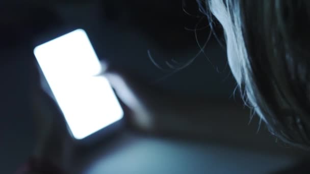 Frau benutzt Smartphone in einem dunklen Raum — Stockvideo