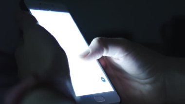 Kadın bir akıllı telefon karanlık bir odada kullanır.