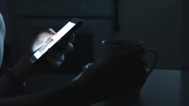 Kadın bir akıllı telefon karanlık bir odada kullanır.