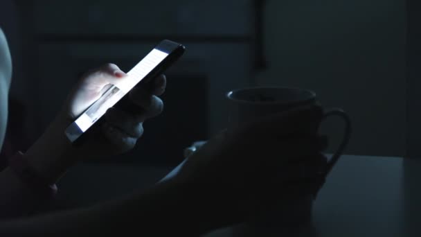 Mulher usa um telefone inteligente em um quarto escuro — Vídeo de Stock