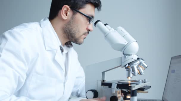 Young scientist looking through microscope — Stock Video