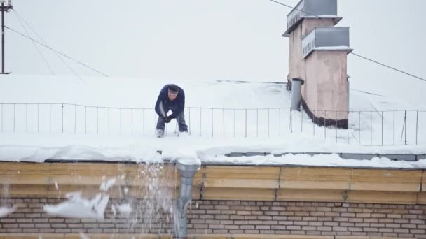 Рабочий убирает снег с крыши после сильного снегопада — стоковое видео