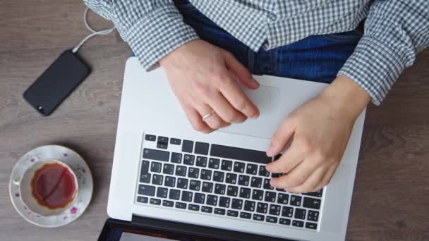 Man aan het werk op laptop geplaatst op houten bureau — Stockvideo