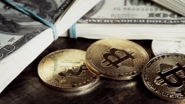 Koin bitcoin pada uang kertas seratus dolar tagihan dalam batch berputar di meja grunge gelap — Stok Video