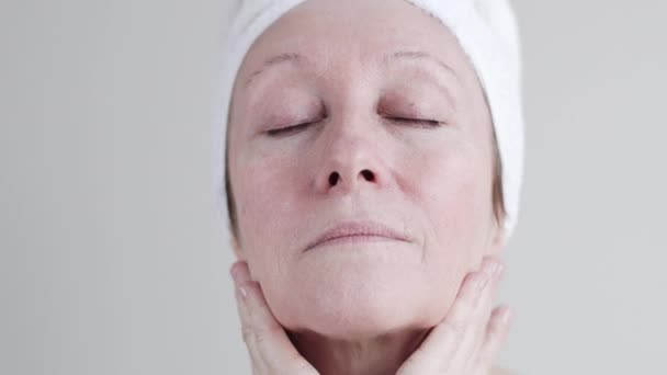 Caucásica mujer de mediana edad aplicando crema a su cara . — Vídeos de Stock