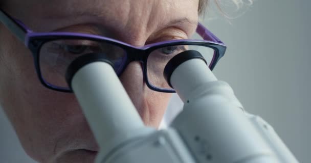 Científica mirando a través del microscopio — Vídeo de stock