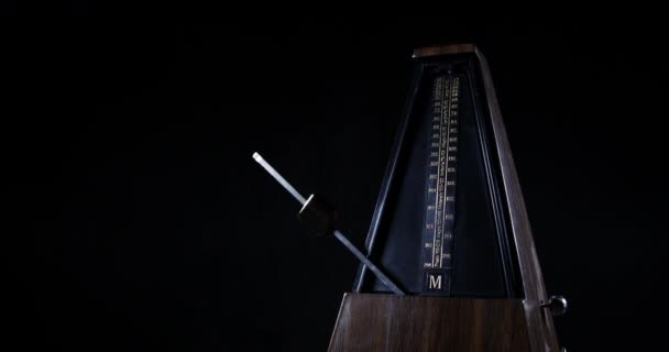 Metrônomo com pêndulo dourado bate ritmo lento no fundo escuro — Vídeo de Stock