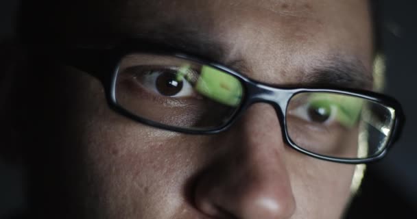 Νεαρός άνδρας με το γυαλί που εργάζονται για το laptop στο σκοτάδι. — Αρχείο Βίντεο