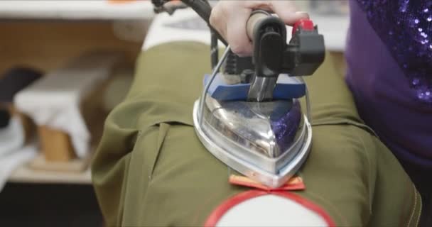 Швея гладильная детали одежды в швейной мастерской — стоковое видео