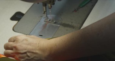 Endüstriyel dikiş makinesinde çalışan kadın terzi..