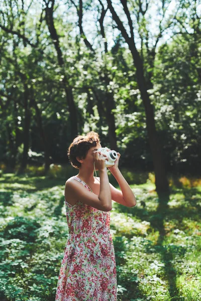 Активна дівчина фотографує миттєву камеру в сонячному лісі — стокове фото