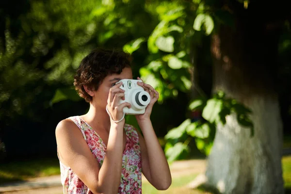 Chica activa tomando fotos en cámara instantánea en el bosque soleado — Foto de Stock