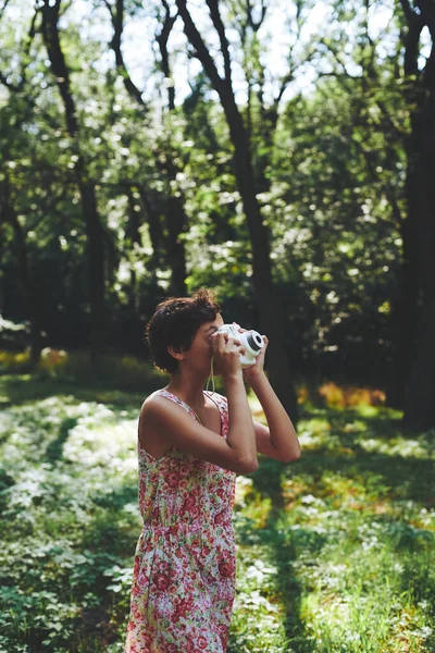 Aktives Mädchen fotografiert mit Sofortbildkamera im sonnigen Wald lizenzfreie Stockfotos