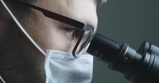 Чоловік-вчений дивиться на мікроскоп — стокове відео