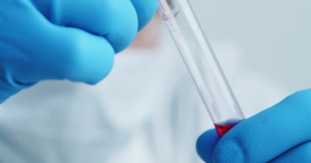 Travailleur médical du laboratoire examine attentivement le sérum dans un tube de verre — Video