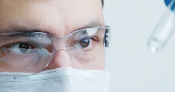 Pracownik medyczny laboratorium dokładnie bada surowicę w szklanej tubce — Wideo stockowe