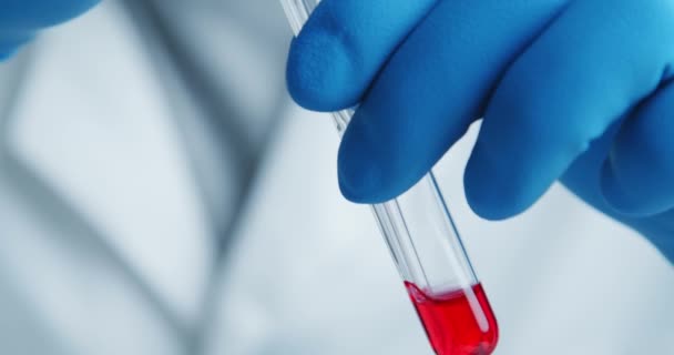 Laboratoriets läkare undersöker noggrant serumet i ett glasrör — Stockvideo