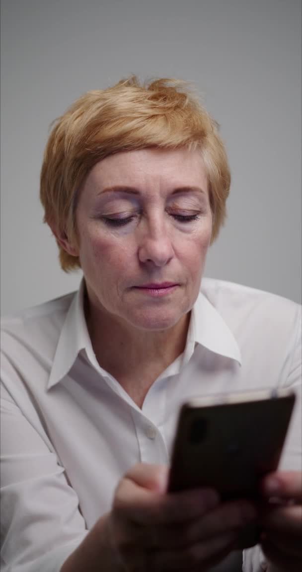 Mulher madura de meia idade segurando smartphone nas mãos e olhando para a tela . — Vídeo de Stock
