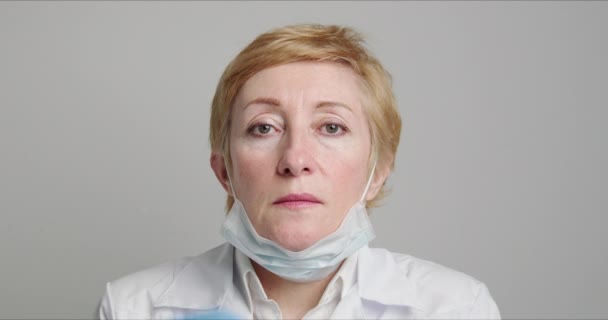 Adult female doctor puts on a medical mask — Αρχείο Βίντεο